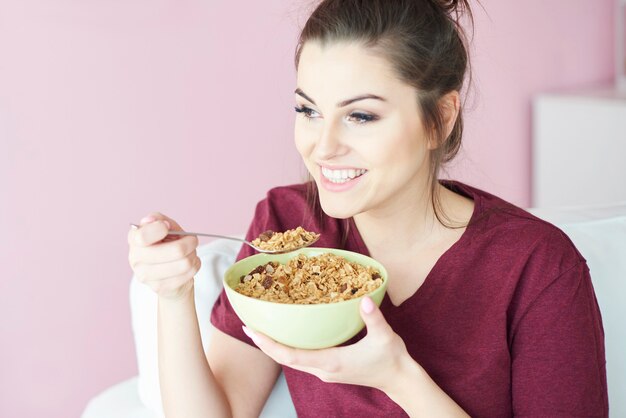 朝食に牛乳とシリアルを持っている若い女性