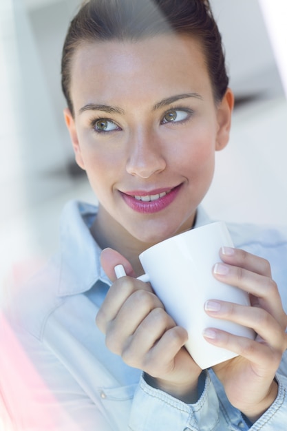 Foto gratuita giovane donna con un caffè in cucina