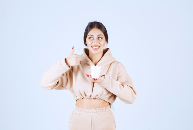 Young woman having a cup of coffee and showing enjoyment sign