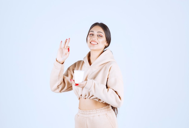 Young woman having a cup of coffee and showing enjoyment sign