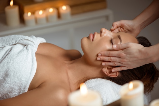 Young woman having face massage relaxing in spa salon.