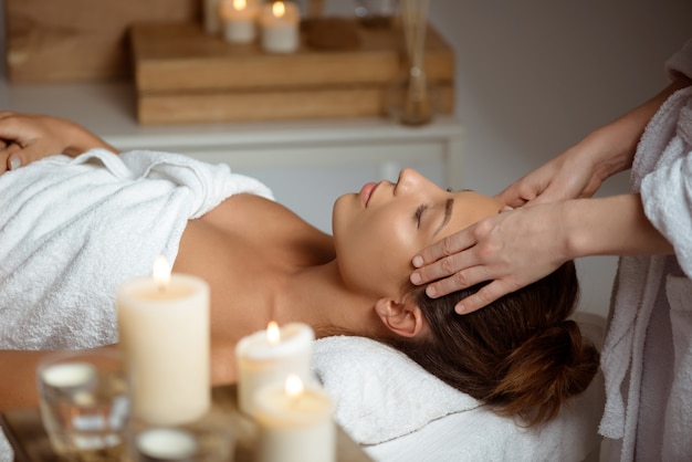 Young woman having face massage relaxing in spa salon.