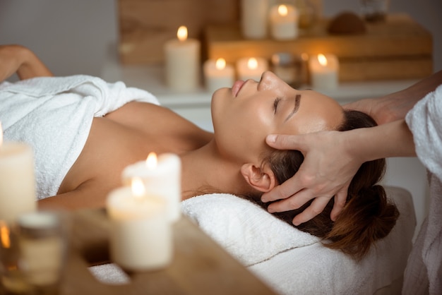 Young woman having face massage relaxing in spa salon.