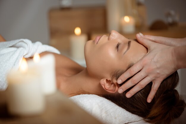 Young woman having face massage relaxing in spa salon.