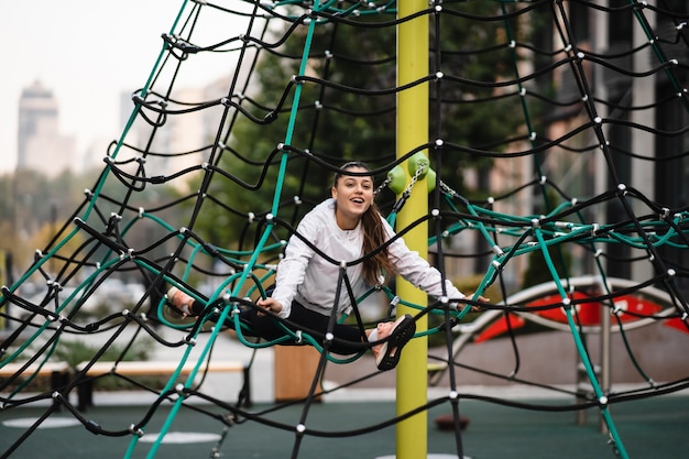 Giovane donna che si diverte sulla piramide di corda nel parco giochi