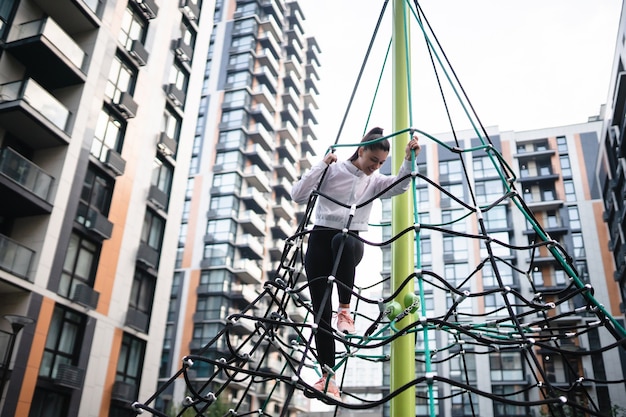 Young woman having fun on the rope pyramid