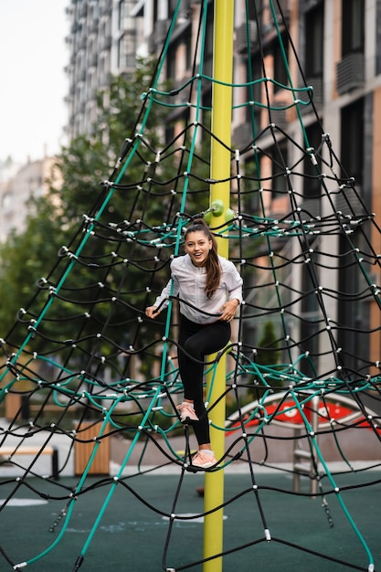 Young woman having fun on the rope pyramid
