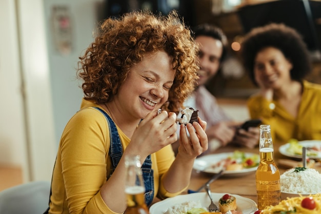 ダイニングテーブルで友達と一緒に座って、デザートを食べながら楽しんでいる若い女性