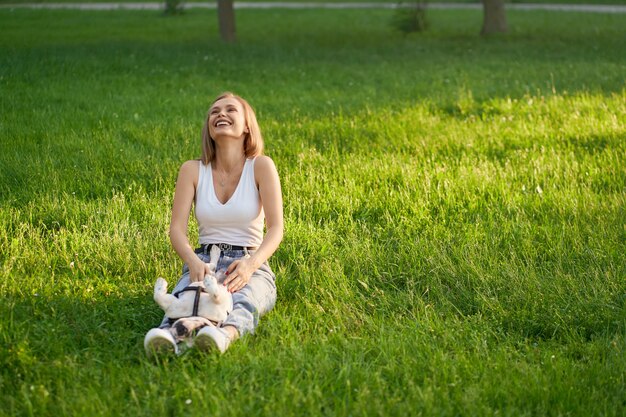 Young woman having fun with french bulldog on grass