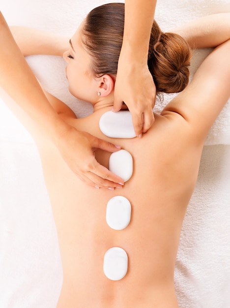 Young woman having hot stone massage in spa salon. Beauty treatment concept.