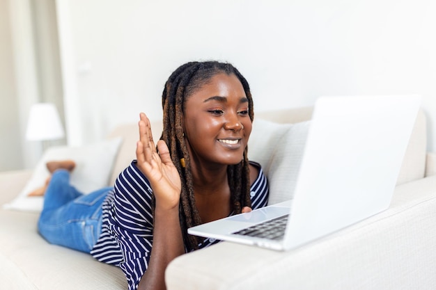 Молодая женщина разговаривает с друзьями онлайн через ноутбук с удивленным выражением лица Женщина не может поверить, что разговаривает с семьей по видеозвонку