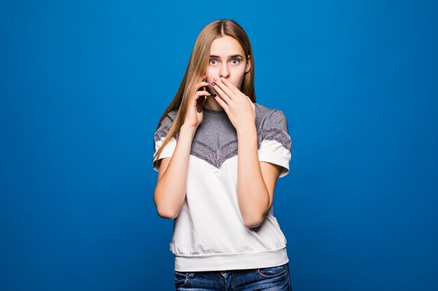 Young woman having a surprised face expression while talking on the telephone