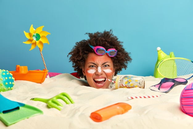 Foto gratuita testa di giovane donna con crema solare sul viso circondato da accessori da spiaggia