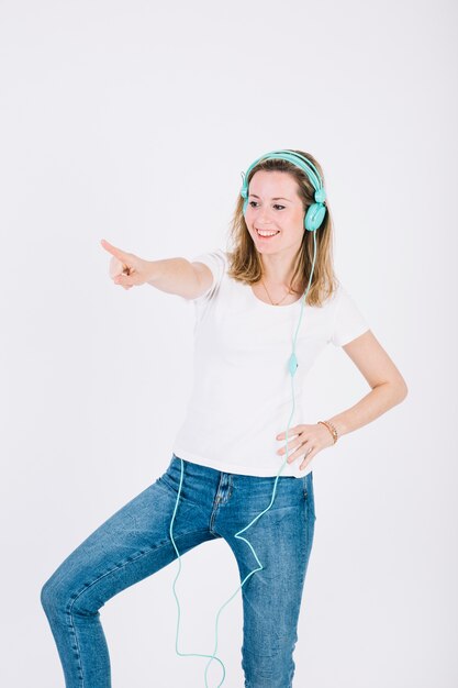 Young woman in headphones dancing on white background