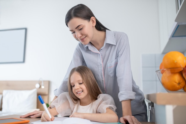 Young woman helping a little girl with homework