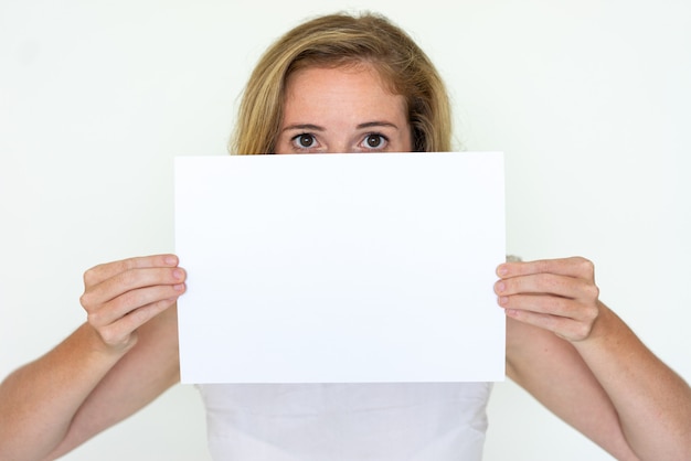 Молодая женщина прячется за чистый лист бумаги