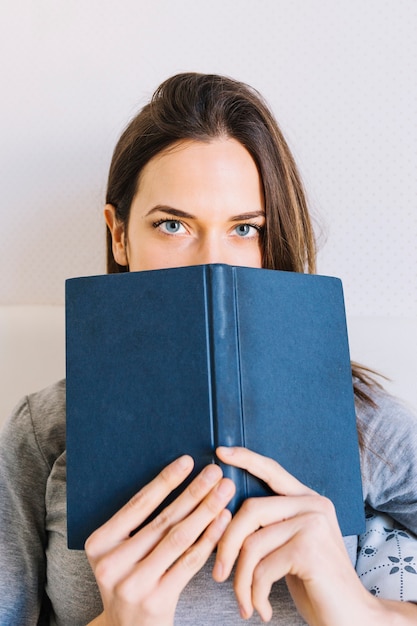 Foto gratuita fronte nascondentesi della giovane donna dietro il libro