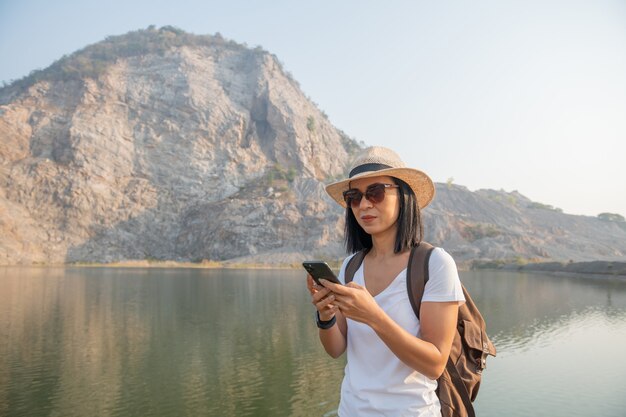 Путешественник молодой женщины использует смартфон, делающий фото на горе