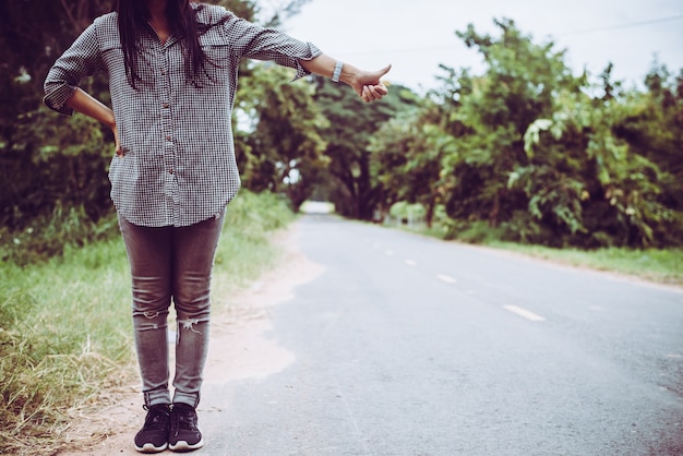 Free photo young woman hitchhiking along a road.