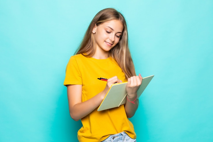 Free Photo young woman hold planner writing on a journal isolated turquoise wall
