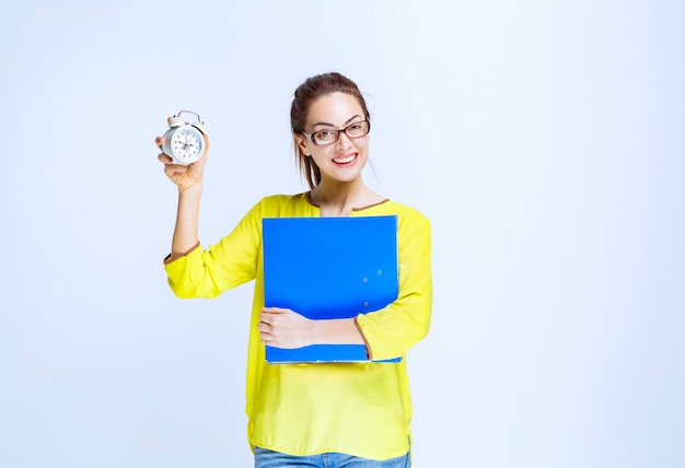 Young woman holding an alarm clock and looks satisfied as she is never late