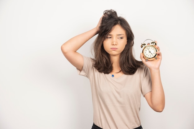 Free photo young woman holding alarm clock on white background