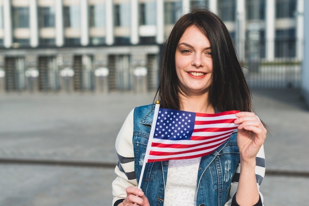 Foto gratuita giovane donna che tiene la bandiera americana il giorno dell'indipendenza