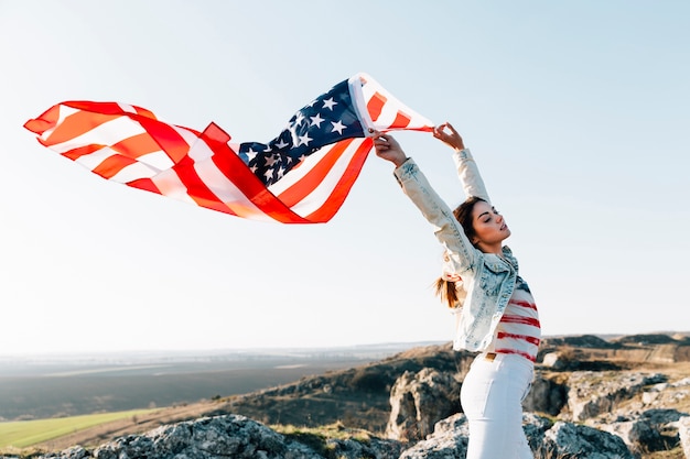 無料写真 山の上にアメリカの国旗を保持している若い女性