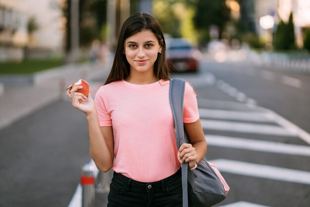 Young woman holding apple against a street background