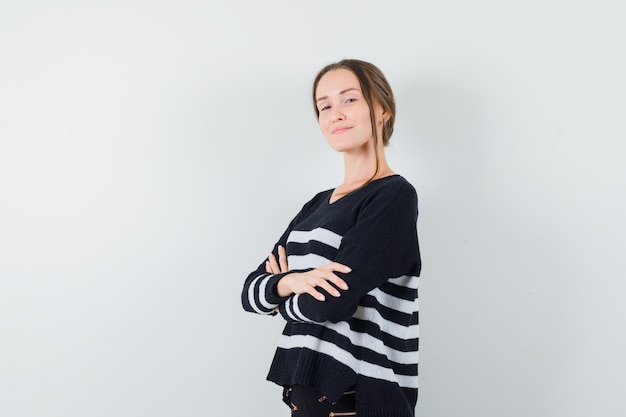 Young woman holding arms crossed in black blouse and black pants and looking confident