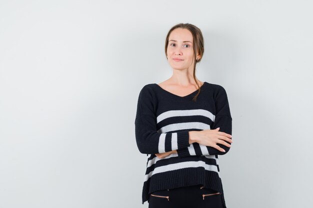 Young woman holding arms crossed in black blouse and black pants and looking happy