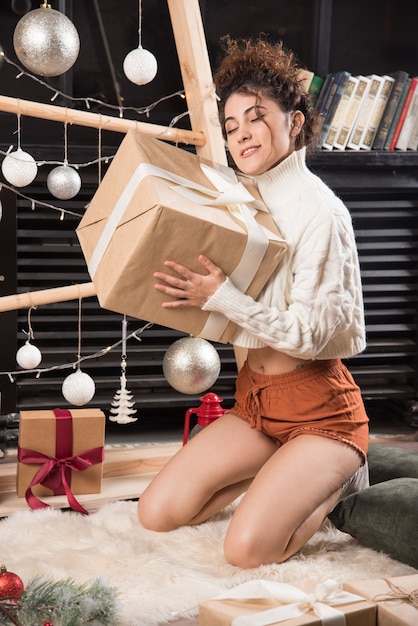 Free photo young woman holding a big box of christmas present