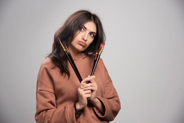 Young woman holding black paint brushes