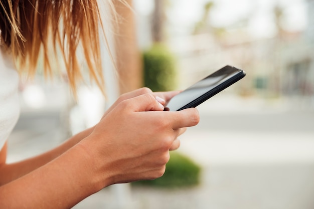 Foto gratuita giovane donna che tiene smartphone nero