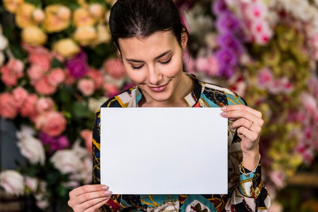 Young woman holding blank paper in green house