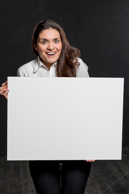 Foto gratuita giovane donna che tiene foglio di carta bianco