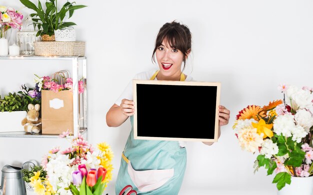 Young woman holding blank slate in floral shop