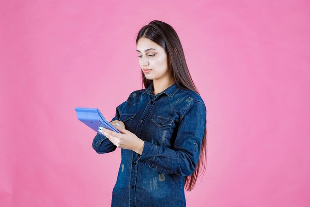 Free photo young woman holding a blue calculator in the hand and calculating