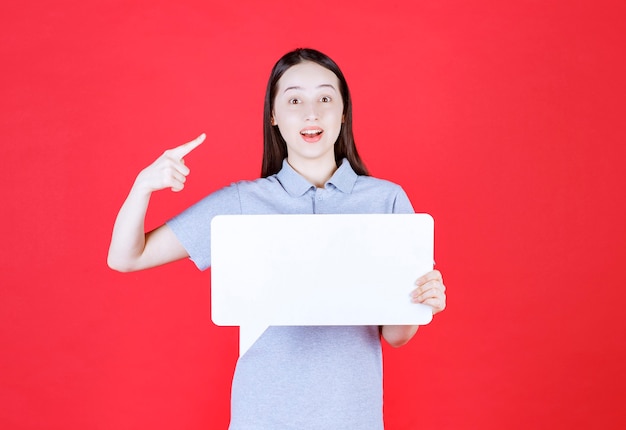 Young woman holding board and point finger to her self