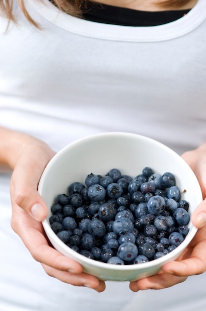 Free photo young woman holding bowl filled blueberries