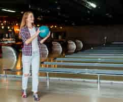 Free photo young woman holding a bowling ball long shot