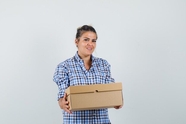 Young woman holding box in checkered shirt.