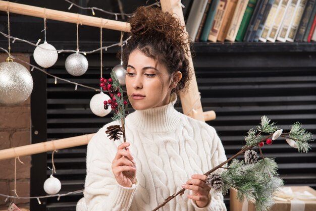 Young woman holding a branch of Christmas holly berry