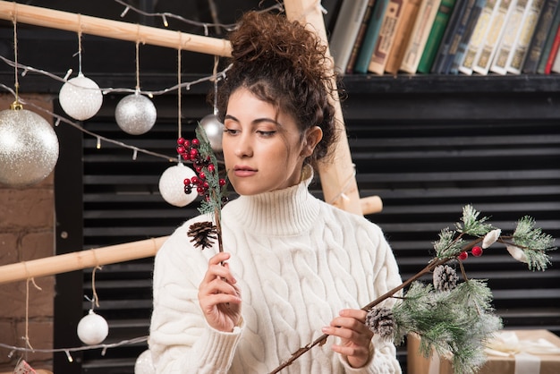 Young woman holding a branch of Christmas holly berry