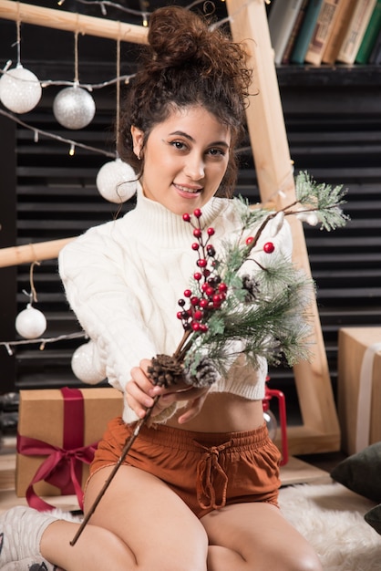 Free photo young woman holding a branch of christmas holly berry