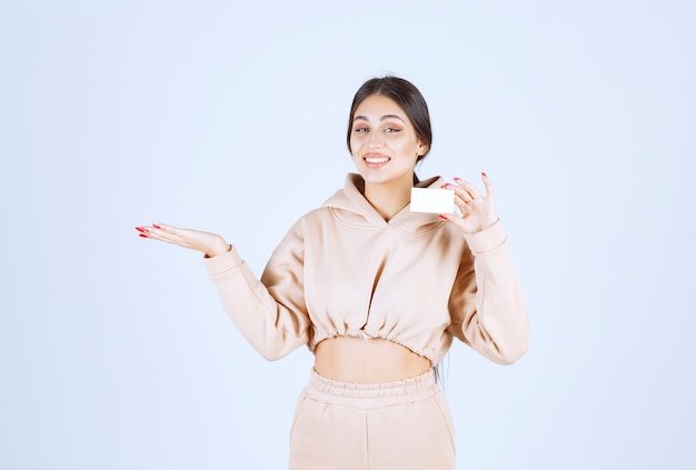 Young woman holding a business card and pointing at somebody