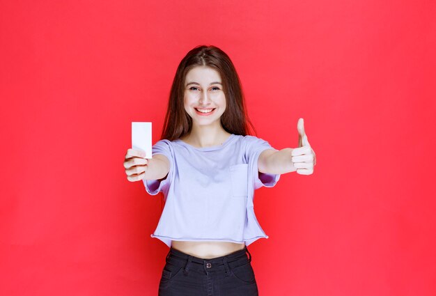 young woman holding a business card and showing thumb up.