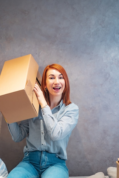 Free photo young woman holding cardboard boxes and shakes it