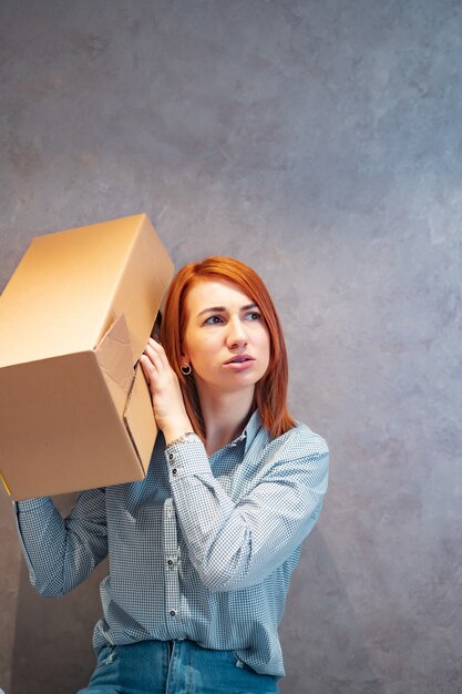 Young woman holding cardboard boxes and shakes it