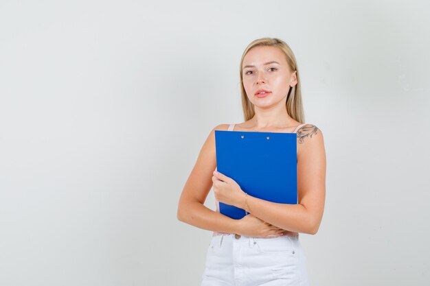 Young woman holding clipboard in singlet, mini skirt and looking busy